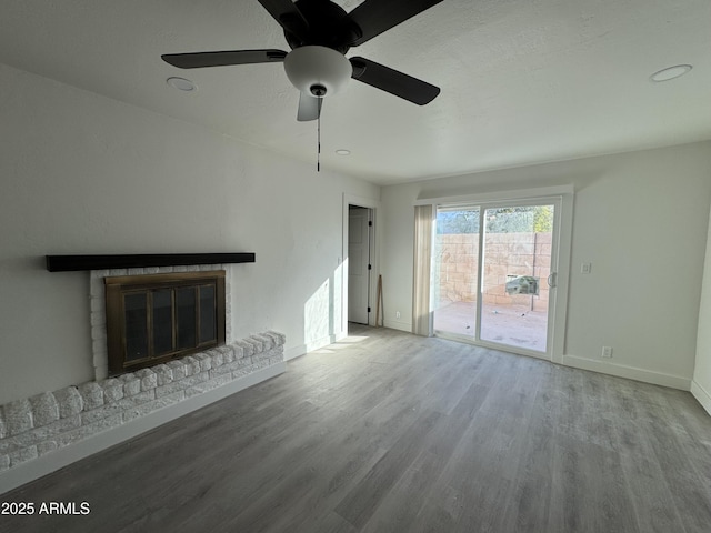 unfurnished living room with ceiling fan, a brick fireplace, and light hardwood / wood-style floors