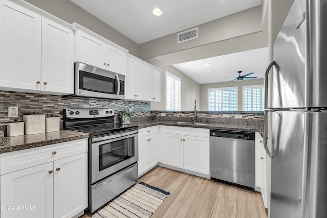 kitchen with stainless steel appliances, sink, white cabinets, and dark stone counters