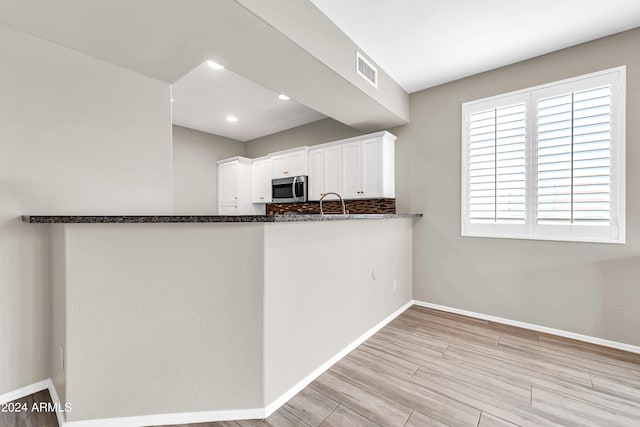 kitchen featuring kitchen peninsula, sink, light hardwood / wood-style flooring, and white cabinets