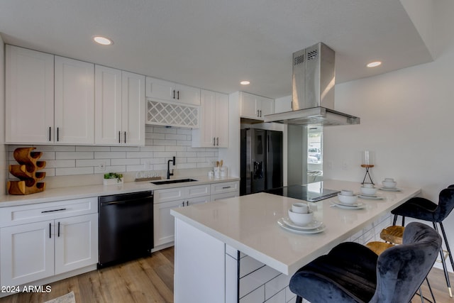 kitchen with island exhaust hood, a breakfast bar, sink, black appliances, and white cabinetry