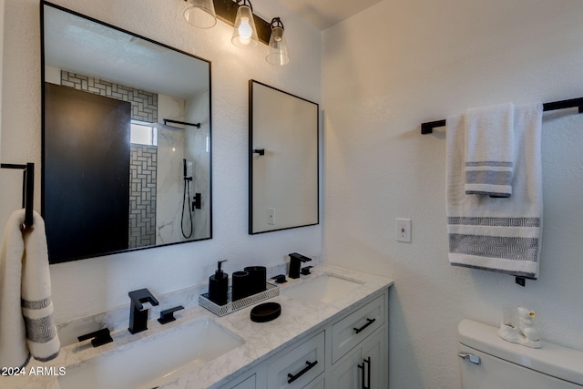 bathroom with vanity, toilet, and a tile shower