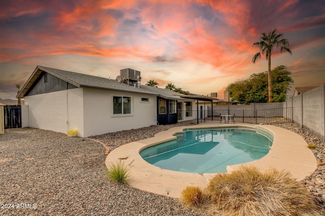 pool at dusk with central air condition unit and a patio