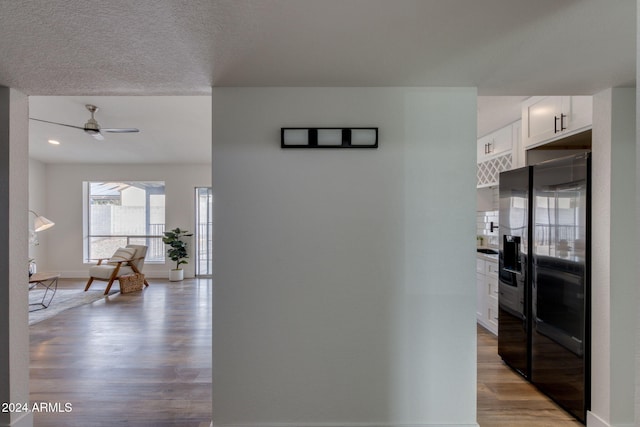 hallway with light hardwood / wood-style flooring and a textured ceiling