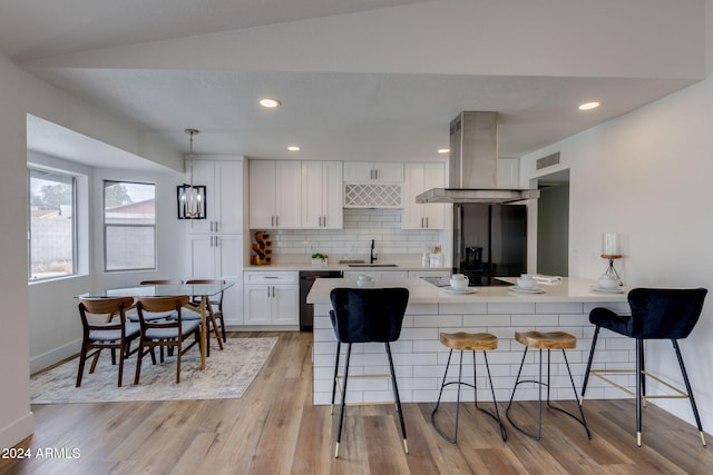 kitchen featuring ventilation hood, sink, white cabinets, light hardwood / wood-style floors, and a breakfast bar area