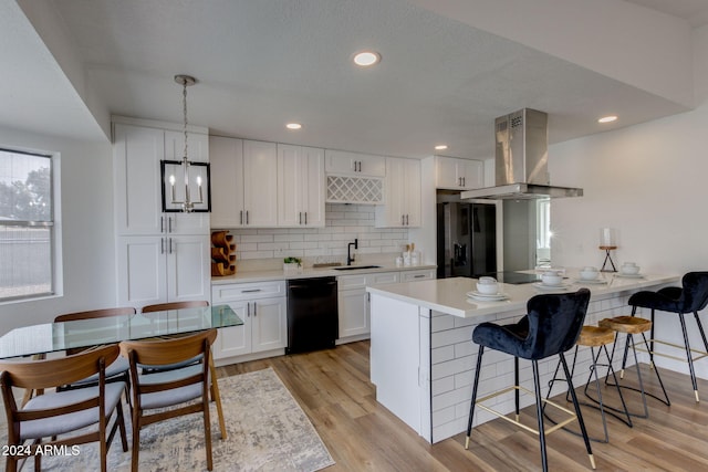 kitchen featuring white cabinets, decorative light fixtures, island range hood, and black appliances