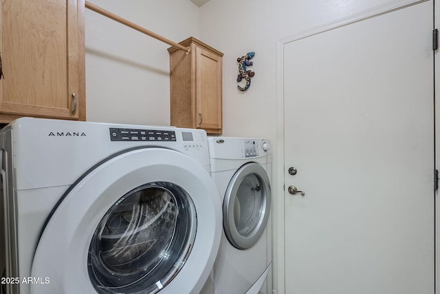 clothes washing area featuring washer and clothes dryer and cabinets