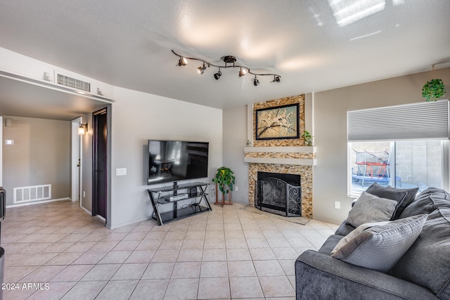 tiled living room featuring a textured ceiling and a large fireplace