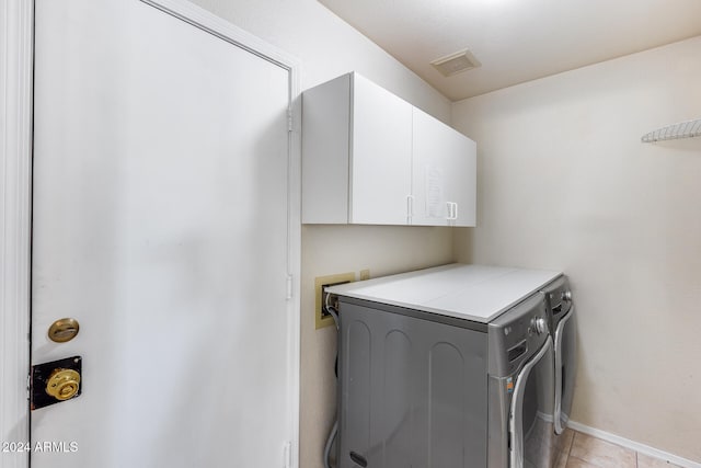 laundry area with light tile patterned flooring, separate washer and dryer, and cabinets