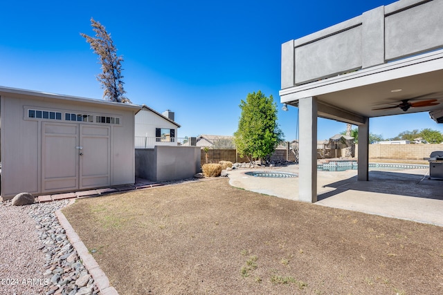 view of yard with a shed, a patio area, a fenced in pool, and ceiling fan