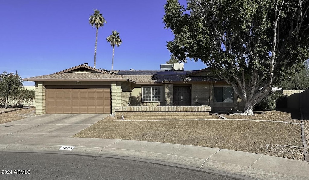 ranch-style home with a garage and solar panels