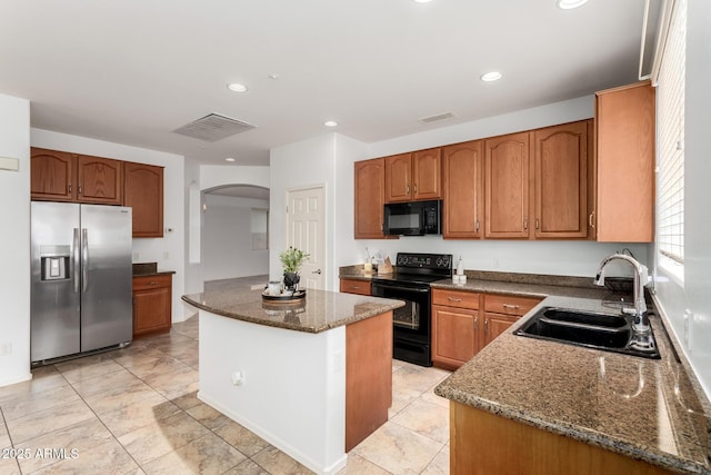 29751 N 119th Ln, Peoria, AZ 85383 - kitchen with black appliances, a sink, arched walkways, dark stone counters, and a kitchen island