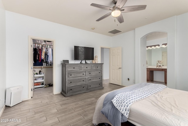 29751 N 119th Ln, Peoria, AZ 85383 - bedroom featuring arched walkways, light wood-style flooring, a spacious closet, a closet, and connected bathroom