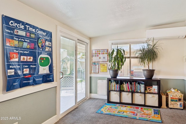 game room with carpet flooring, a wall mounted AC, and a textured ceiling