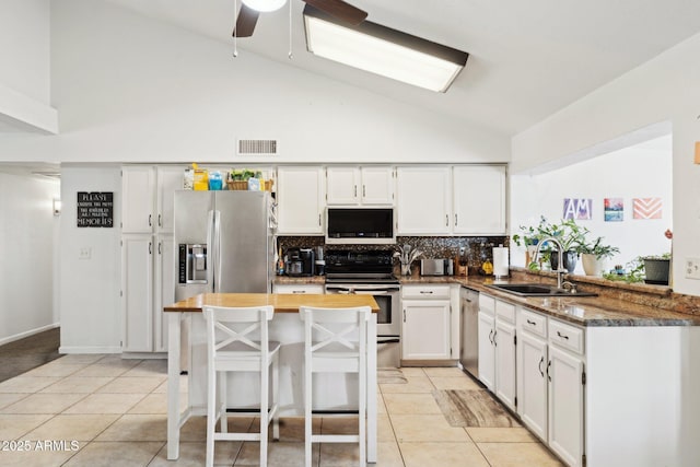 kitchen with sink, stainless steel appliances, white cabinets, and light tile patterned flooring