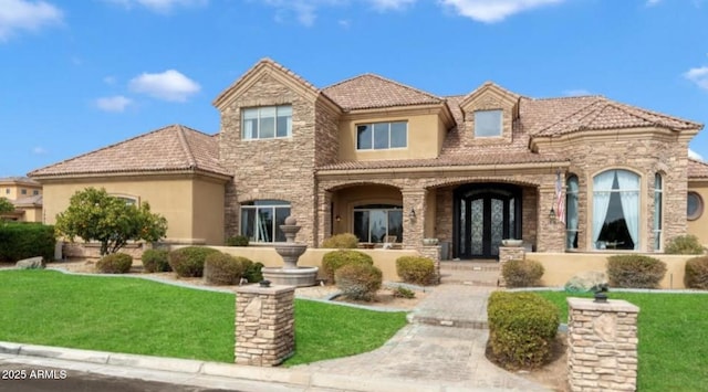 view of front of house with stone siding, a tile roof, french doors, a front yard, and stucco siding