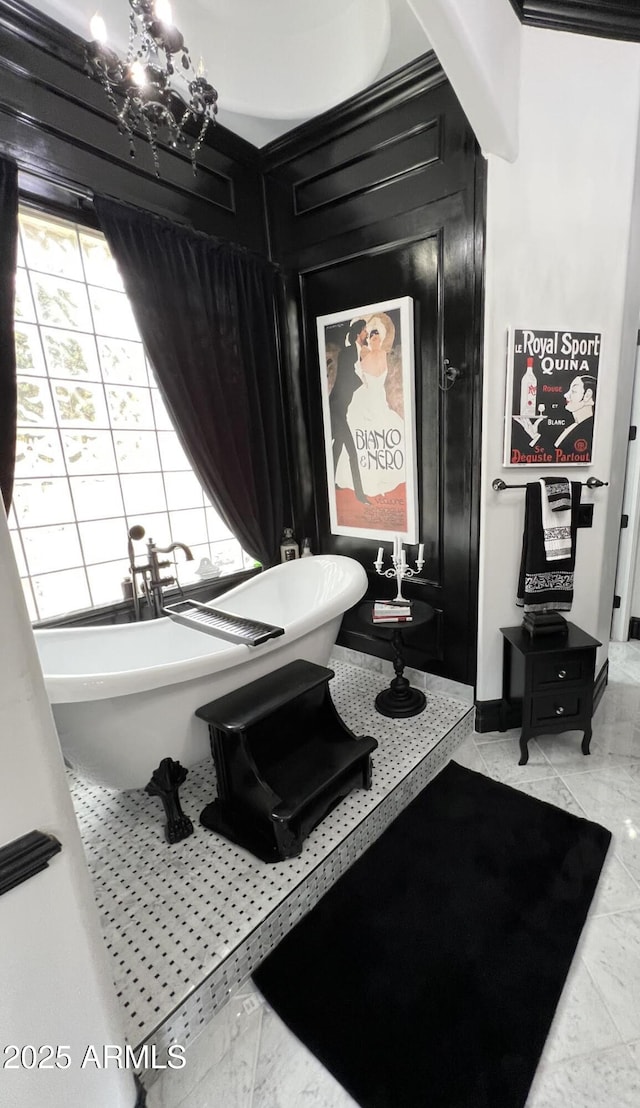 bathroom with a soaking tub, a notable chandelier, and marble finish floor