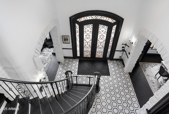 tiled entryway featuring baseboards and arched walkways