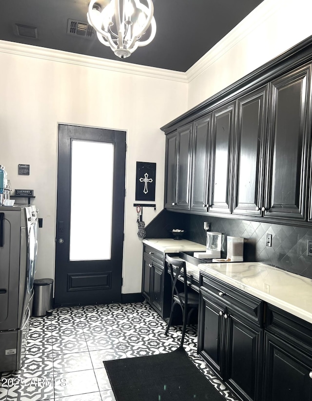 washroom with ornamental molding, a chandelier, washing machine and clothes dryer, visible vents, and cabinet space