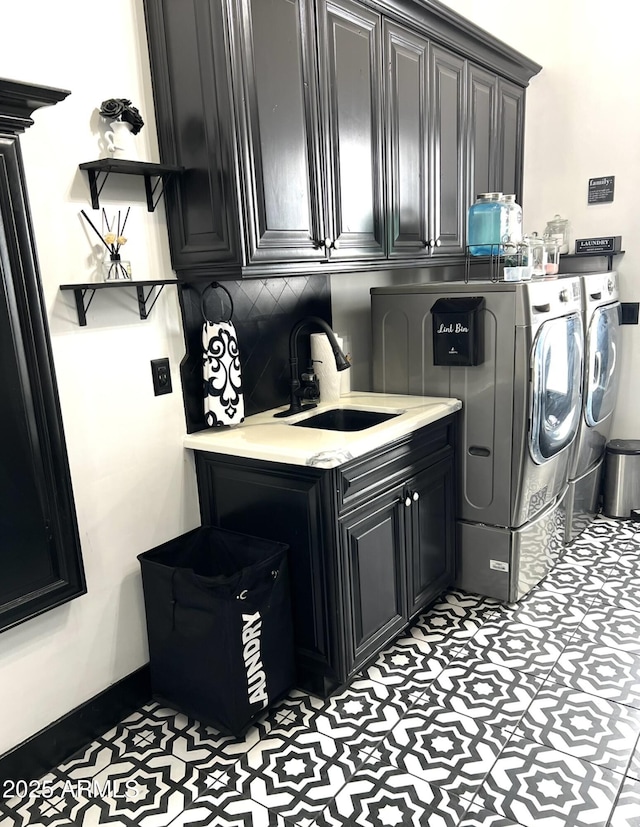 washroom with baseboards, cabinet space, a sink, and separate washer and dryer