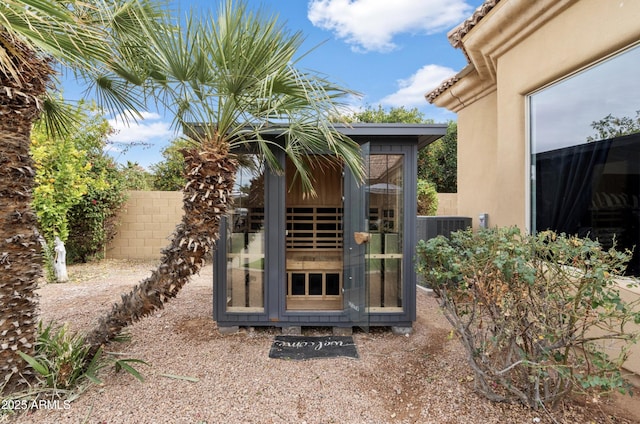 exterior space featuring an outbuilding, fence, and cooling unit