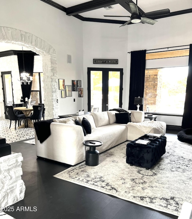 living area with ceiling fan with notable chandelier, beamed ceiling, visible vents, and a wealth of natural light