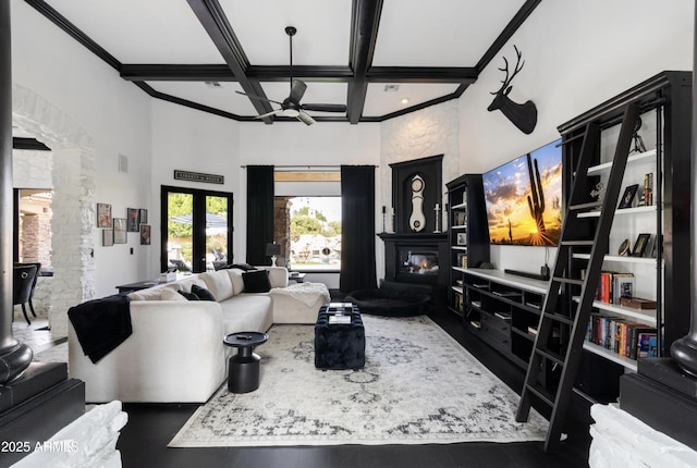 living area featuring coffered ceiling, decorative columns, beam ceiling, a high ceiling, and ceiling fan