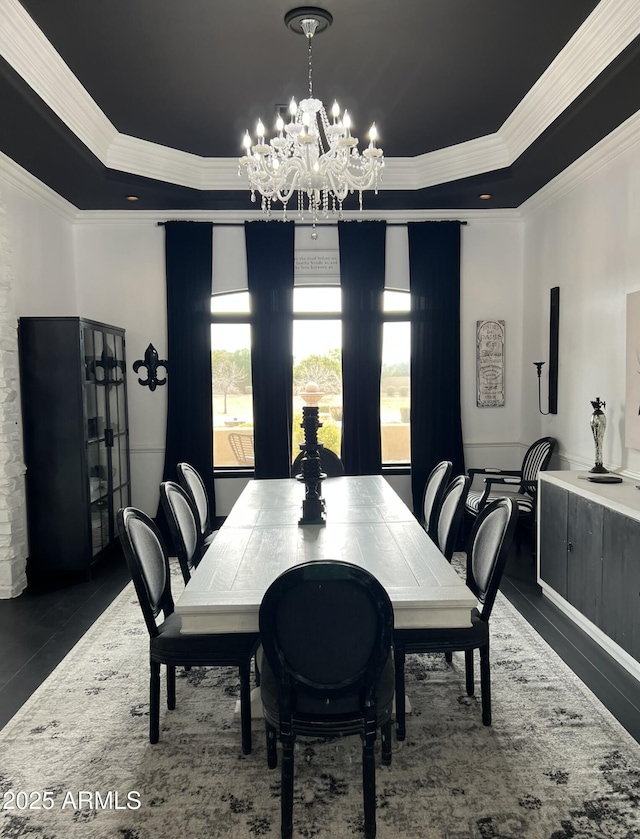 dining area featuring a raised ceiling, crown molding, and a chandelier