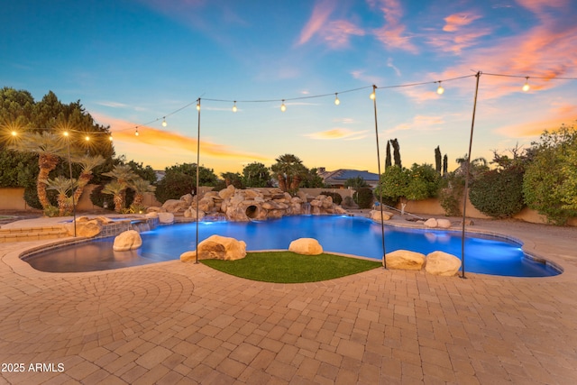 pool at dusk with a patio and a pool with connected hot tub