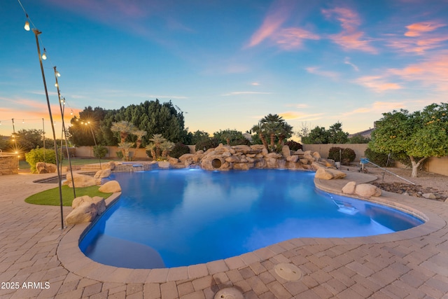 pool at dusk with a fenced backyard, a pool with connected hot tub, and a patio