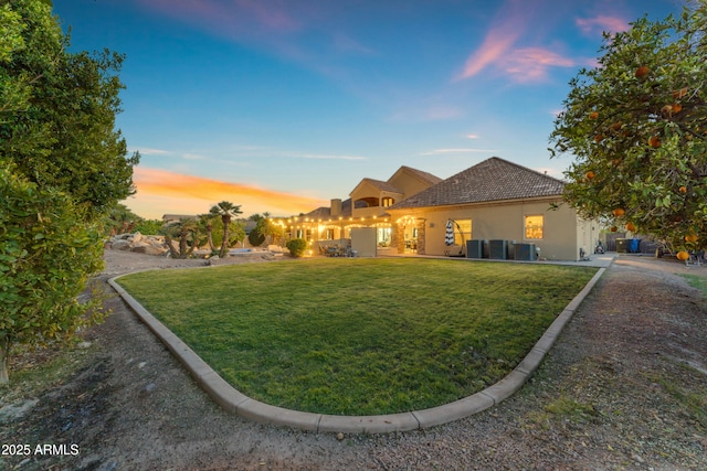 view of front of home featuring cooling unit, a lawn, and stucco siding