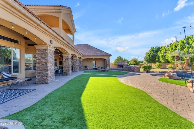 view of yard featuring a patio, fence, and a fireplace
