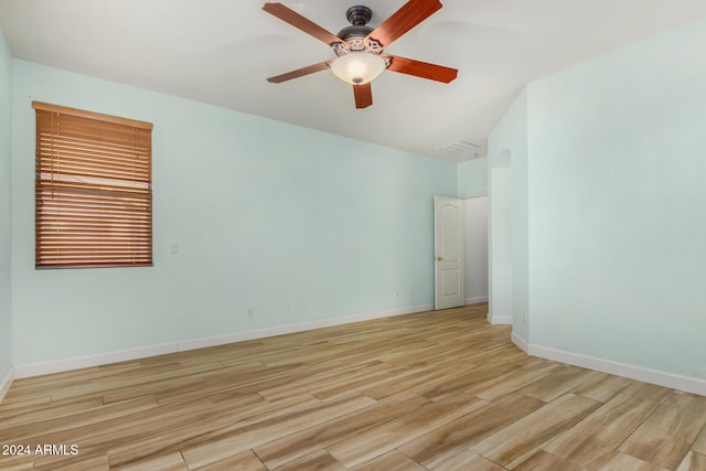 spare room with light wood-type flooring, vaulted ceiling, and ceiling fan