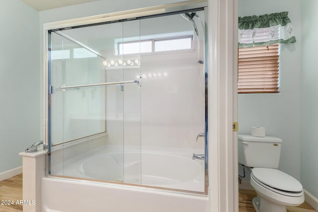 bathroom with hardwood / wood-style floors, toilet, and bath / shower combo with glass door