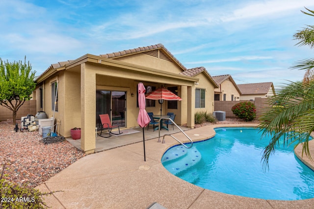 view of swimming pool with cooling unit and a patio area