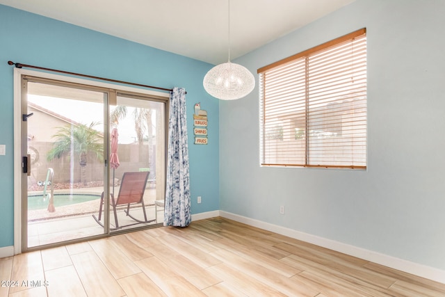 spare room featuring a chandelier, hardwood / wood-style floors, and a wealth of natural light