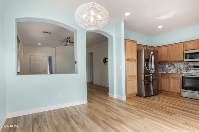 kitchen featuring hanging light fixtures, stainless steel appliances, backsplash, light hardwood / wood-style floors, and ceiling fan with notable chandelier