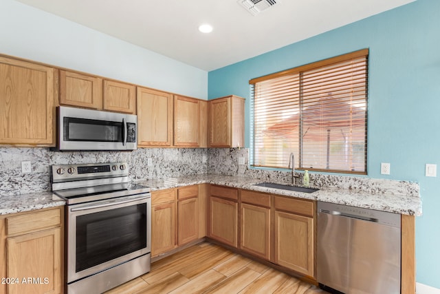 kitchen featuring decorative backsplash, sink, stainless steel appliances, and light hardwood / wood-style floors