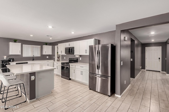 25539 W Gwen St, Buckeye, AZ 85326 - kitchen with stainless steel appliances, a sink, wood finish floors, a kitchen bar, and light countertops