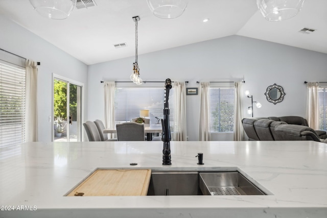 kitchen with light stone countertops, decorative light fixtures, and vaulted ceiling