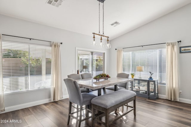 dining space with dark wood-type flooring and vaulted ceiling