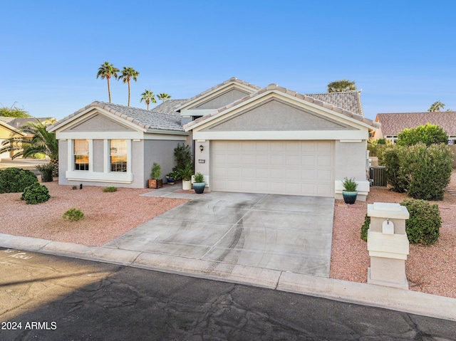 ranch-style home featuring a garage and cooling unit