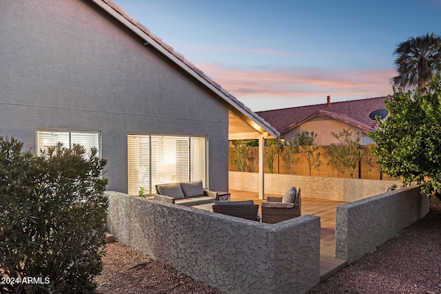 patio terrace at dusk featuring outdoor lounge area and a wooden deck