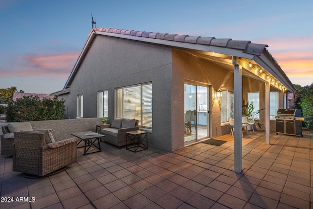 patio terrace at dusk with an outdoor living space and area for grilling