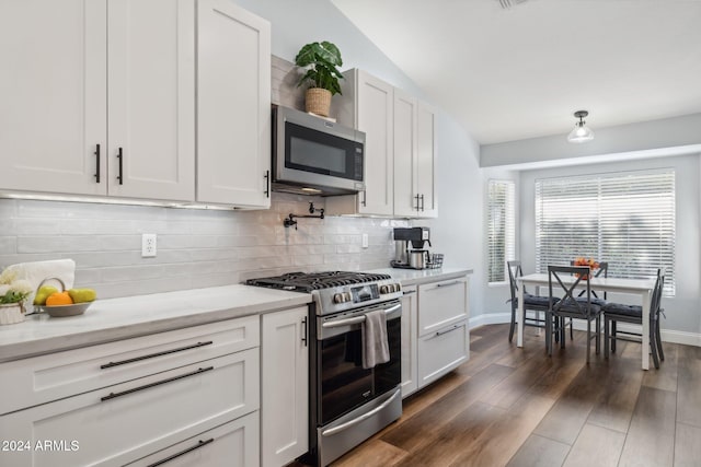 kitchen featuring dark hardwood / wood-style flooring, lofted ceiling, white cabinets, decorative backsplash, and appliances with stainless steel finishes