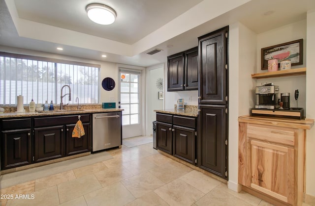 kitchen featuring light stone counters, sink, a raised ceiling, and dishwasher