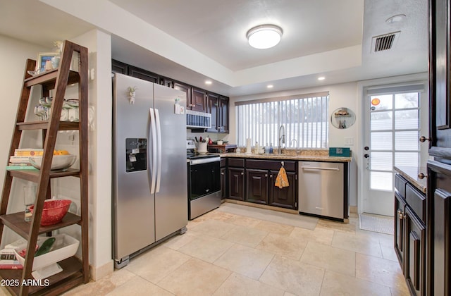 kitchen with dark brown cabinetry, sink, stainless steel appliances, and light tile patterned flooring