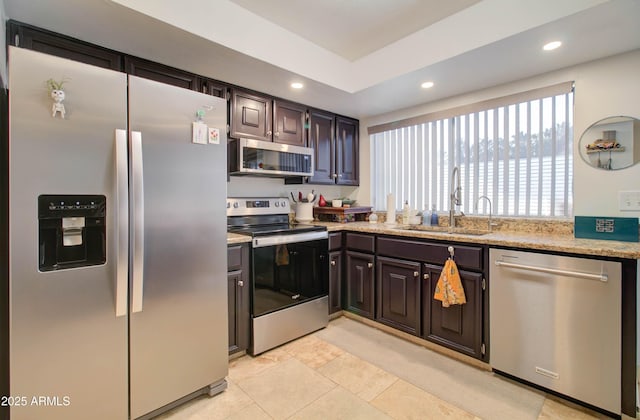 kitchen with sink, stainless steel appliances, dark brown cabinetry, light stone countertops, and light tile patterned flooring