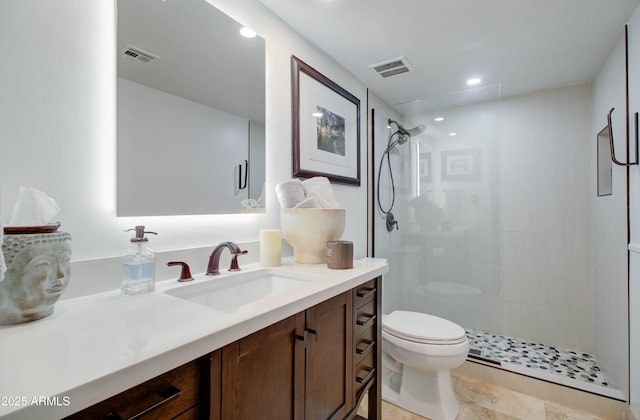 bathroom featuring vanity, a shower with shower door, and toilet