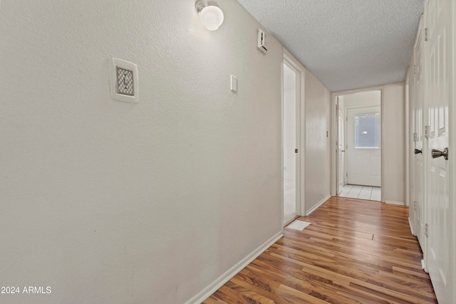 hall featuring light hardwood / wood-style flooring and a textured ceiling