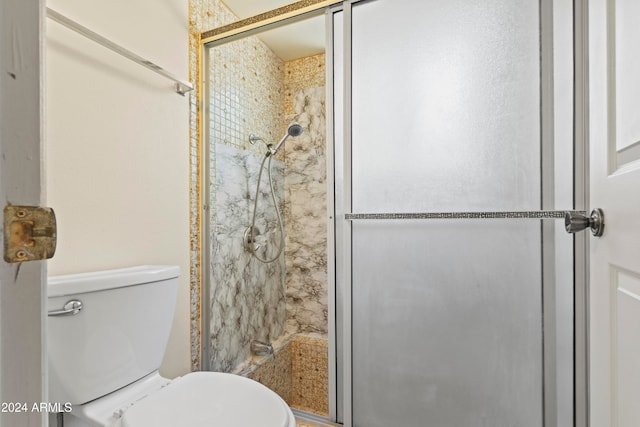 bathroom featuring toilet and a shower with shower door